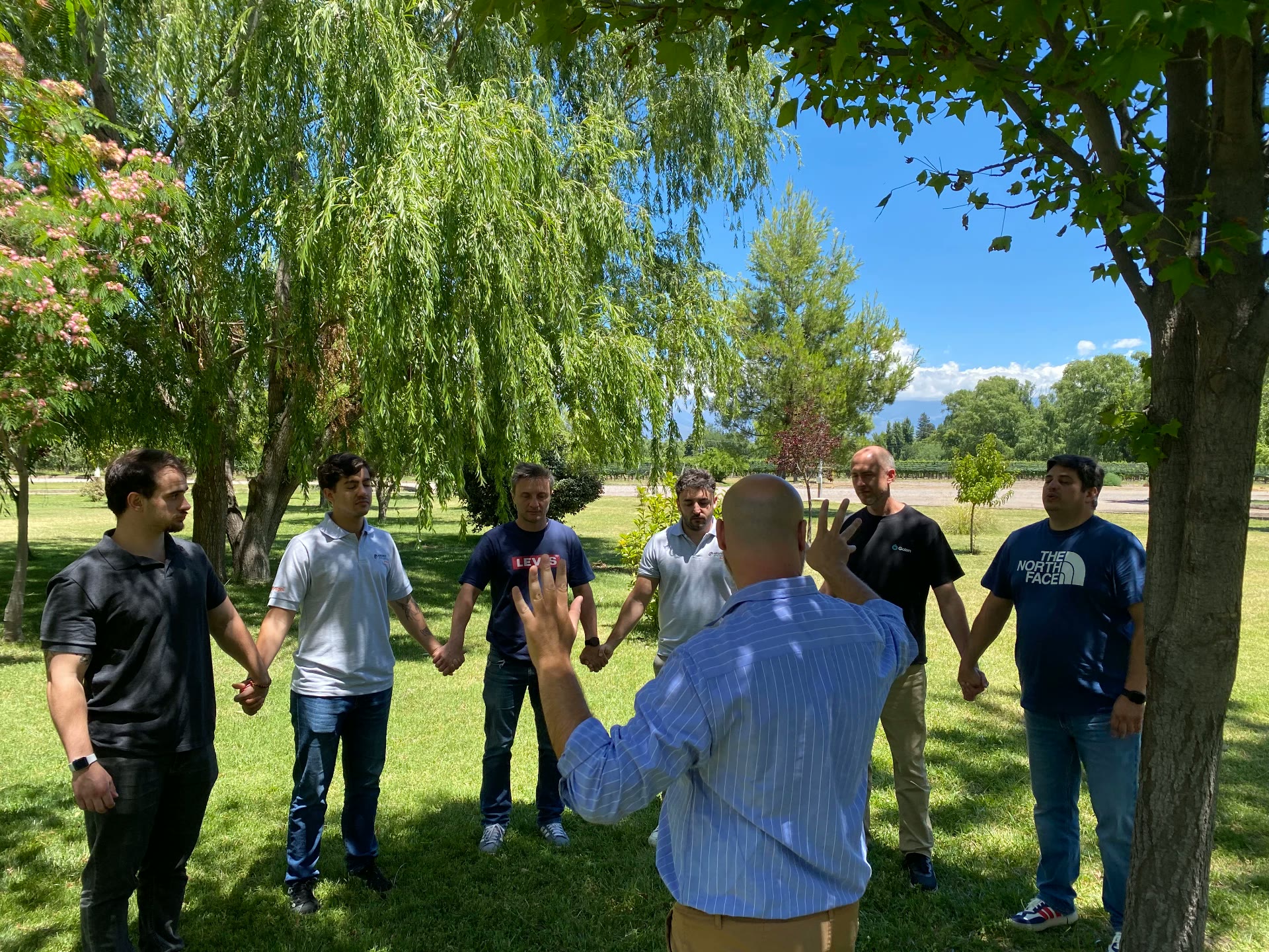 Círculo de participantes tomados de las manos en un parque